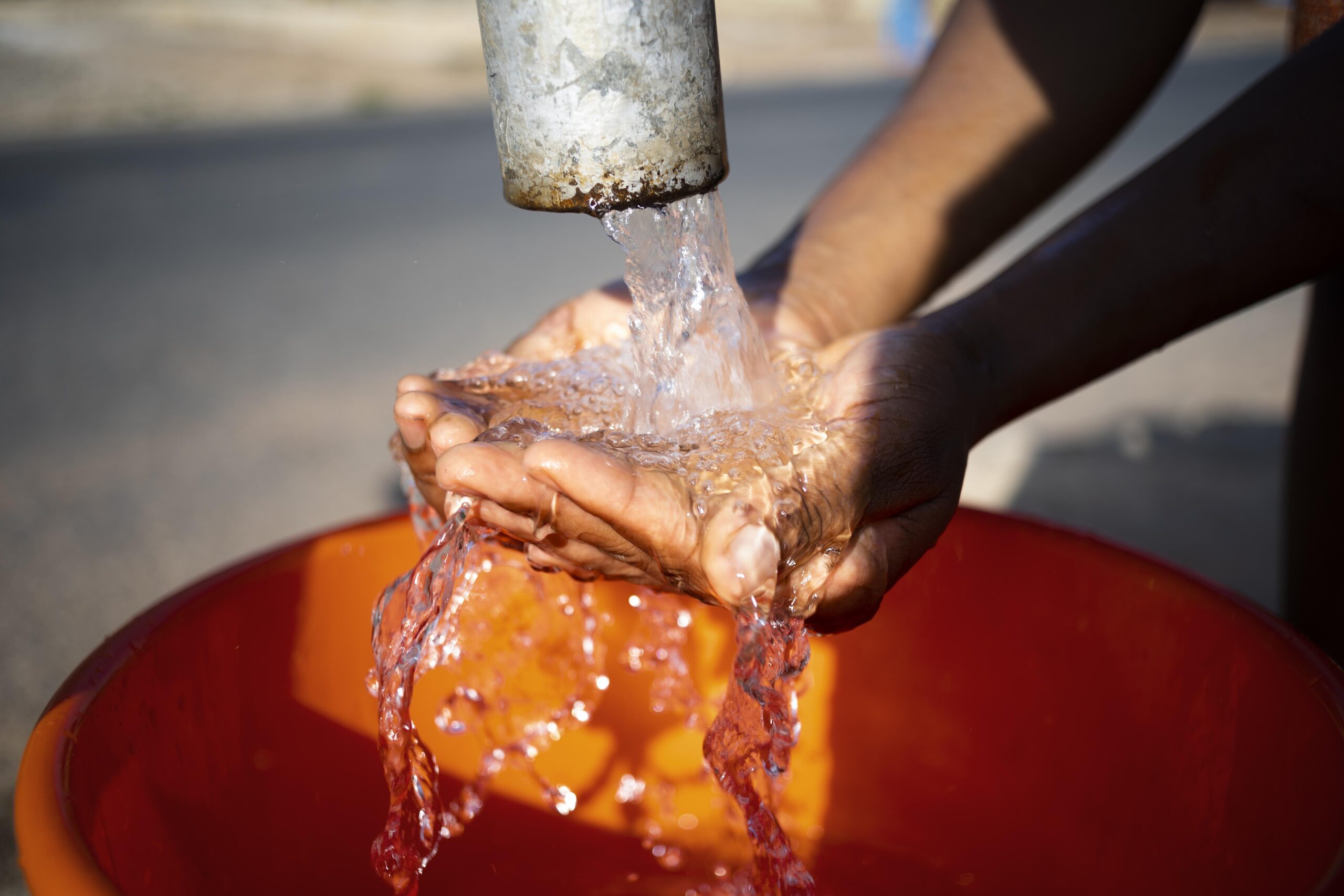 Femme africaine versant de l'eau dans un récipient à l'extérieur